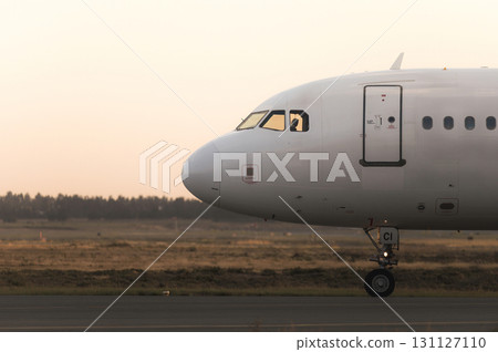 Airplane taxiing on runway at sunset with pilot in cockpit 131127110