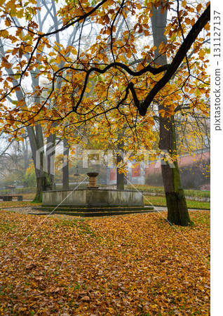 A beautiful autumn scene of the fountain in front of Cesky Krumlov Castle, surrounded by trees with golden leaves, blending nature and historic architecture in a serene atmosphere A beautiful autumn scene of the fountain in front of Cesky Krumlov Castle, surrounded by trees with golden leaves, blending nature and historic architecture in a serene atmosphere 131127137