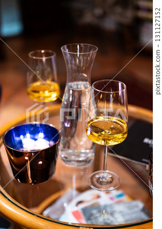 A close-up shot of a table with a modern wine glass filled with white wine, capturing the elegance of the glass and the refined atmosphere of the setting 131127152