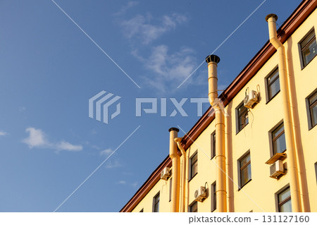 Air conditioners on the facade of a yellow house against a blue sky. An air ventilation. Air conditioners on the facade of a yellow house against a blue sky. An air ventilation. 131127160