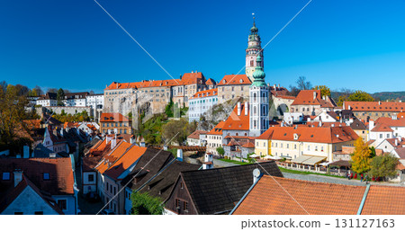 Panoramic view of Cesky Krumlov, featuring the historic castle tower and the church of St. John of Nepomuk. The medieval town's charm is beautifully captured on a sunny day 131127163