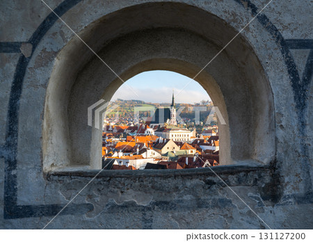 Church of St. Vitus in Cesky Krumlov surrounded by the historic town center. A sunny day with a clear blue sky highlights the charm of this UNESCO-listed medieval destination 131127200