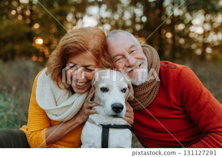 Elderly man and woman walking their dog in nature on autumn day. Elderly man and woman walking their dog in nature on autumn day. 131127291