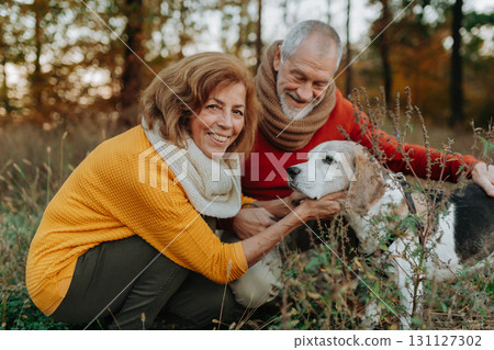 Elderly man and woman walking their dog in nature on autumn day. Elderly man and woman walking their dog in nature on autumn day. 131127302