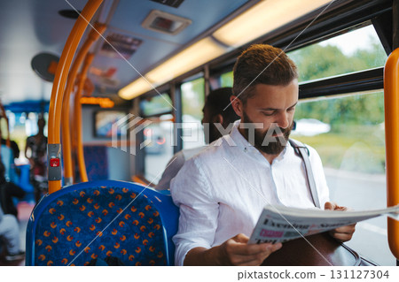 Man sitting in bus and reading newspapers, travelling to work. 131127304