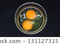 Preparing Scrambled Eggs. Two Raw Eggs In A Glass Plate On Black Surface Top View   131127315