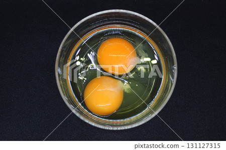 Preparing Scrambled Eggs. Two Raw Eggs In A Glass Plate On Black Surface Top View   131127315