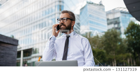 Handsome businessman working in park, making phone call with client. Handsome businessman working in park, making phone call with client. 131127319