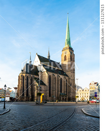A photograph of the Cathedral of St. Bartholomew in Plzen, Czech Republic. This Gothic cathedral with its iconic tower stands proudly, surrounded by historic buildings, offering a stunning view 131127615