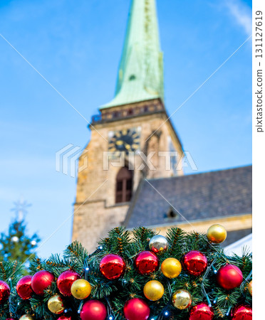 A festive scene with Christmas decorations in the foreground and the Cathedral of St. Bartholomew in Plzen, Czech Republic, in the background. A charming mix of tradition and holiday spirit A festive scene with Christmas decorations in the foreground and the Cathedral of St. Bartholomew in Plzen, Czech Republic, in the background. A charming mix of tradition and holiday spirit 131127619