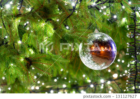 A beautiful glass ornament hanging on a Christmas tree, reflecting the lively atmosphere of the square in Pilsen, capturing the essence of the holiday spirit A beautiful glass ornament hanging on a Christmas tree, reflecting the lively atmosphere of the square in Pilsen, capturing the essence of the holiday spirit 131127627