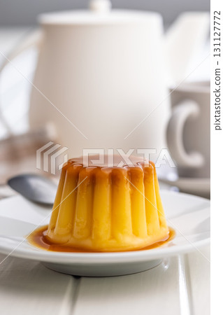 Vanilla pudding with caramel sauce on plate on white table. Vanilla pudding with caramel sauce on plate on white table. 131127772
