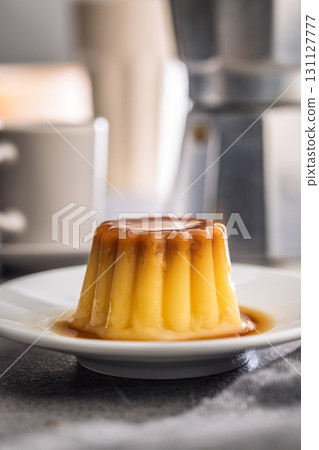 Vanilla pudding with caramel sauce on plate on kitchen table. 131127777