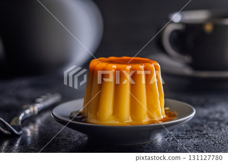 Vanilla pudding with caramel sauce on plate on black table. Vanilla pudding with caramel sauce on plate on black table. 131127780