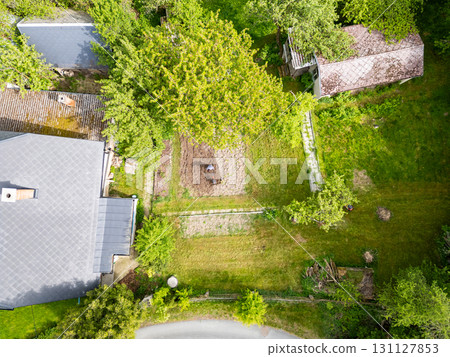 Young farmer man is cultivating the field with machine. Aerial drone top down view of small field in old fashioned garden. Concept of home agriculture. 131127853