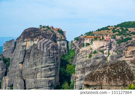 Monastery Meteora Greece. Stunning summer panoramic landscape. View at mountains and green forest against epic blue sky with clouds. UNESCO heritage list object. 131127864