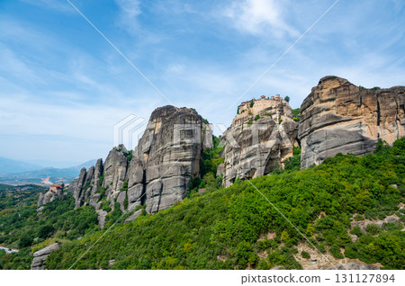 Monastery Meteora Greece. Stunning summer panoramic landscape. View at mountains and green forest against epic blue sky with clouds. UNESCO heritage list object. 131127894