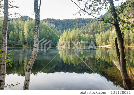The Piskovna lake in Adrspach-Teplice Rocks area, in Hradec Kralove Region in the Czech Republic, Europe. A serene lake surrounded by lush green forest, creating a calming and reflective atmosphere. 131128021