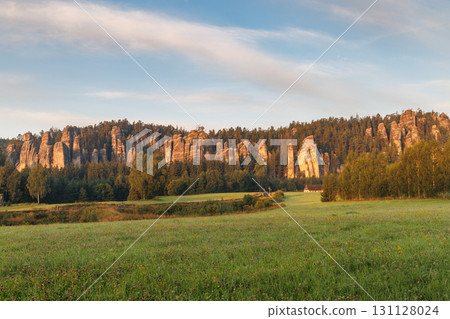 Adrspach-Teplice Rocks, sandstone formations in Hradec Kralove Region in the Czech Republic, Europe. Scenic landscape featuring towering rock formations along a dense forest edge under a blue sky. 131128024