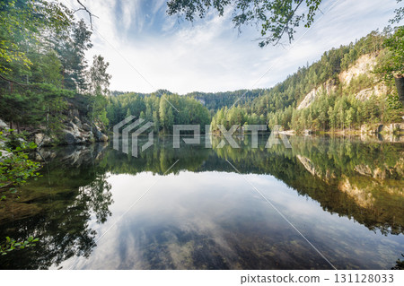 The Piskovna lake in Adrspach-Teplice Rocks area, in Hradec Kralove Region in the Czech Republic, Europe. Reflections of trees and sky create a serene scene on the tranquil waters of the lake. 131128033