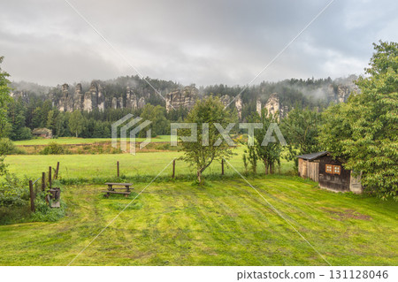 Landscape of Adrspach-Teplice Rocks area, in Hradec Kralove Region in the Czech Republic, Europe. Scenic landscape with rock formations shrouded in mist, a field, and a rustic shed on a cloudy day. Landscape of Adrspach-Teplice Rocks area, in Hradec Kralove Region in the Czech Republic, Europe. Scenic landscape with rock formations shrouded in mist, a field, and a rustic shed on a cloudy day. 131128046