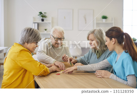 Senior people collecting geometric figures sitting at table in nursing home with young nurse Senior people collecting geometric figures sitting at table in nursing home with young nurse 131128350