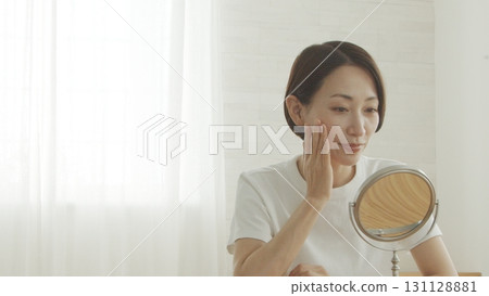一位 40 多歲的日本女性對著鏡子檢查自己的皮膚狀況 一位 40 多歲的日本女性對著鏡子檢查自己的皮膚狀況 131128881