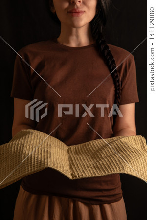 brunette girl stands with a warm smile holding fresh bread in her hands. She is dressed in a simple brown T shirt creating a cozy atmosphere. 131129080
