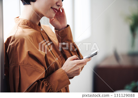 A woman's hand operating a smartphone by the window 131129088