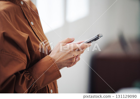 A woman's hand operating a smartphone by the window 131129090
