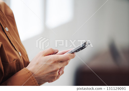 A woman's hand operating a smartphone by the window 131129091