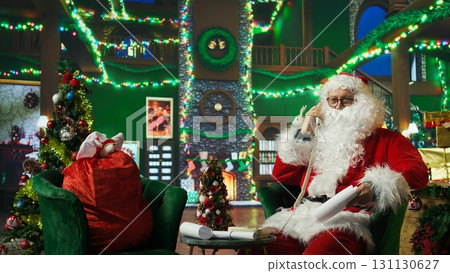 Santa Claus answering phone call, responding to kids requesting gifts. Person impersonating Santa Claus talking with children about Christmas gifts using landline telephone, camera A Santa Claus answering phone call, responding to kids requesting gifts. Person impersonating Santa Claus talking with children about Christmas gifts using landline telephone, camera A 131130627