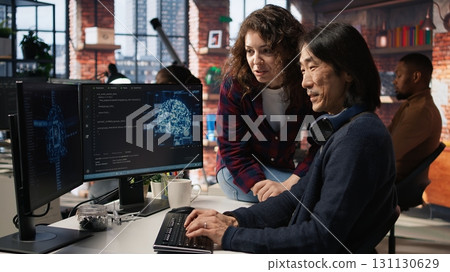 Happy programmer coming to AI startup office CTO manager desk to request help with building application. Upbeat employee asks questions to senior team leader in software development agency, camera A 131130629