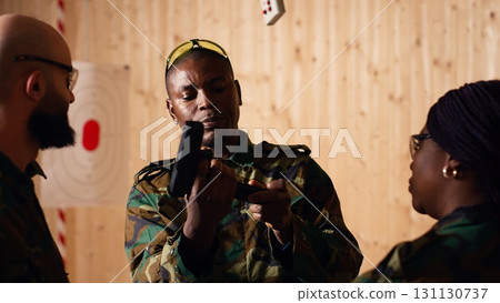 Army commander talking with recruits in shooting gallery, showing them how to reload firearms. Military officer instructing soldiers on how to load ammunition into pistol, camera B Army commander talking with recruits in shooting gallery, showing them how to reload firearms. Military officer instructing soldiers on how to load ammunition into pistol, camera B 131130737