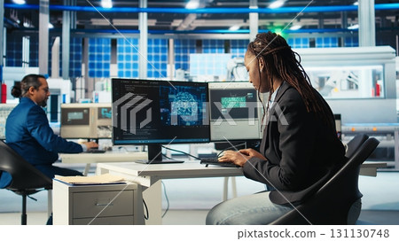 System administrator in photovoltaics factory using AI to diagnose malfunctioning systems. Solar panels manufacturing plant software developer reducing downtime using artificial intelligence, camera A 131130748