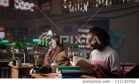 African american girl does bachelor paper research for citations and other information, using the database at the campus library. Intelligent student working on her diploma. Camera B. African american girl does bachelor paper research for citations and other information, using the database at the campus library. Intelligent student working on her diploma. Camera B. 131130782