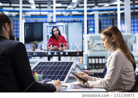 Shareholders in production plant doing research during teleconference meeting. Investors and factory management analyzing strategies for equipment manufacturing expansion during online videocall 131130975