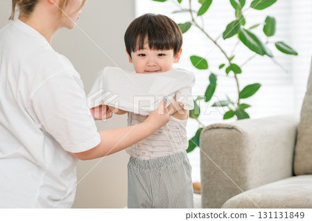 一位母親在家裡的客廳幫兒子穿衣服 一位母親在家裡的客廳幫兒子穿衣服 131131849