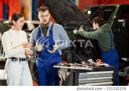 Woman talking to mechanic about car repair process 131132159
