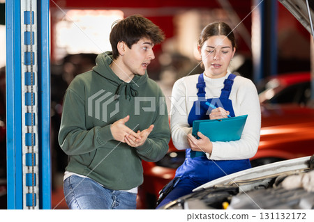 male client consults with a mechanic to repair a car male client consults with a mechanic to repair a car 131132172