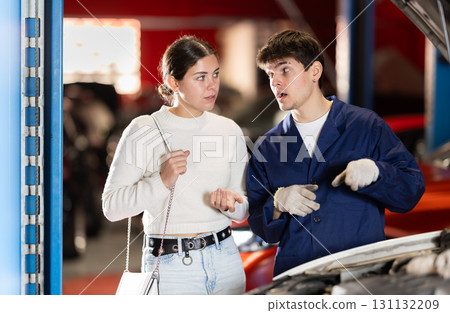 woman consults a mechanic in a car service 131132209