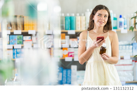Woman scans cough syrup on her phone at pharmacy 131132312