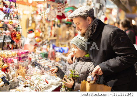 Man with son in outdoor souvenir shop examines Christmas toys Man with son in outdoor souvenir shop examines Christmas toys 131132345