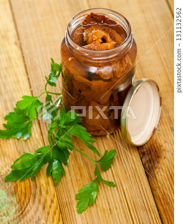 Pickled red pine mushrooms in open jar with parsley 131132562