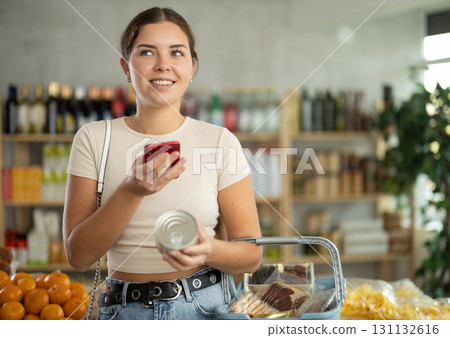 Young woman scanning qr code of canned food Young woman scanning qr code of canned food 131132616