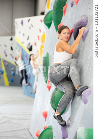 Young woman practicing rock climbing on climbing wall 131132721