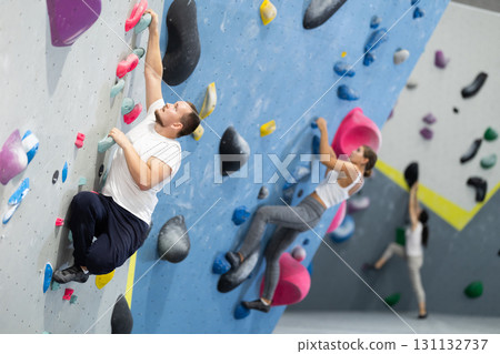 Man climbing a tall, indoor, man made rock climbing wall Man climbing a tall, indoor, man made rock climbing wall 131132737