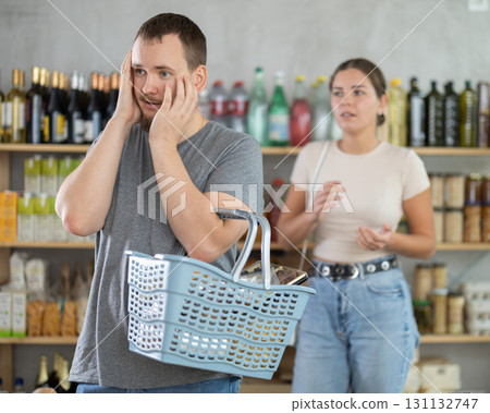 Wife stands behind husband and yells at companion in shop 131132747