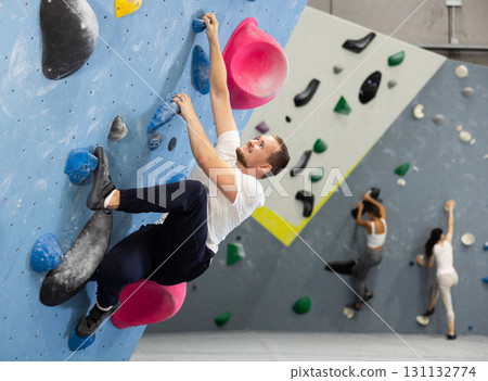 Young man practicing rock climbing on climbing wall Young man practicing rock climbing on climbing wall 131132774