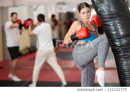Girl punches and kicks punching bag in gym. Girl punches and kicks punching bag in gym. 131132775